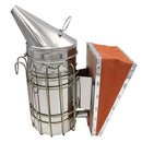 A stainless steel bee smoker with a hand pump and heat shield, alongside a metal grid for holding the smoky material.
